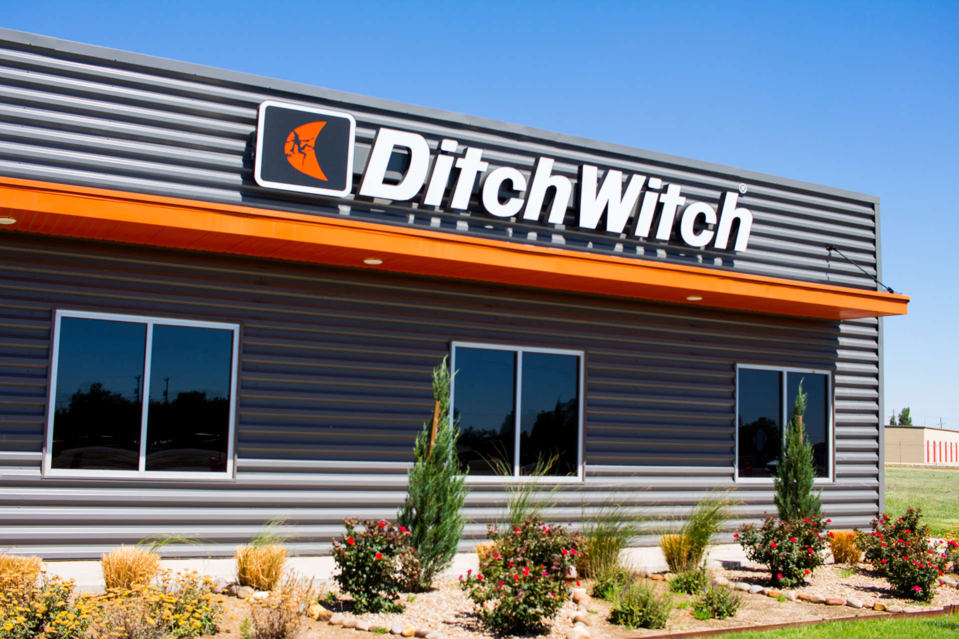 Ditch Witch from the front of building with rocks and landscaping